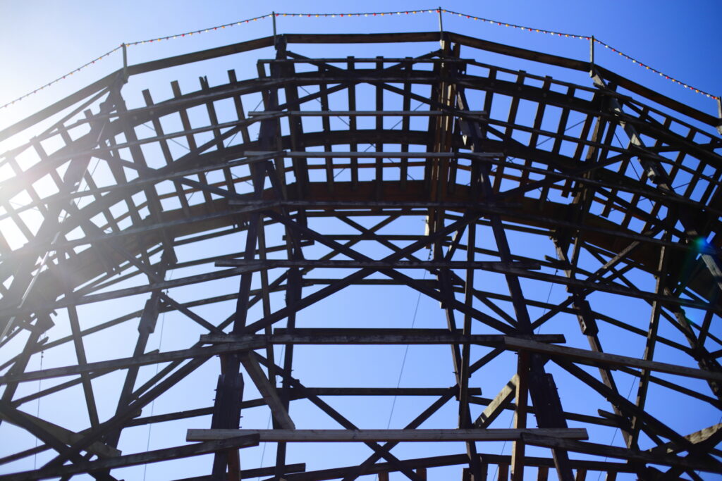 An old, wooden roller coaster track, backlit by the sun.