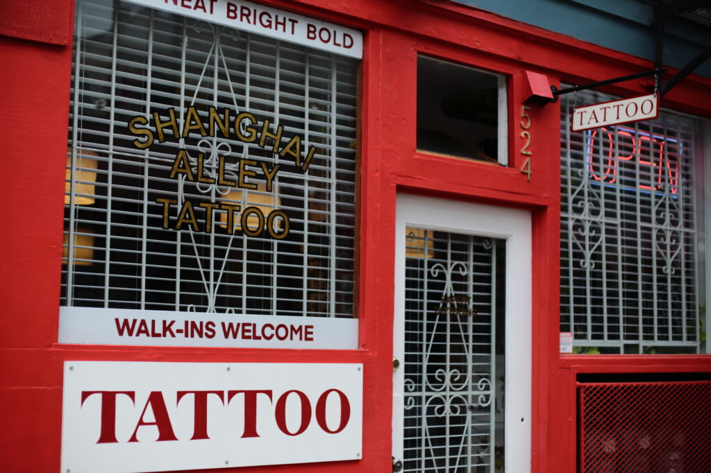 The bright red entrance to a tattoo shop advertising "Walk-ins Welcome."