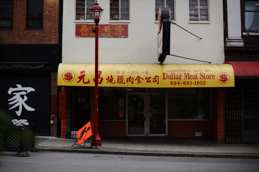 A yellow awning above a closed Chinese meat shop on an empty street.